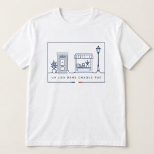 T-shirt blanc avec « UN LIEN DANS CHAQUE RUE » en bleu marine et une illustration au trait d’une porte, d’une boutique et d’un lampadaire, dans un cadre rectangulaire souligné d’un accent tricolore sur le devant.
